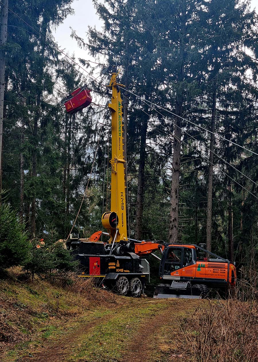 Maschinen von Markus Klausner im Wald, Waldweg im Vordergund, Nadelbäume im Hintergrund
